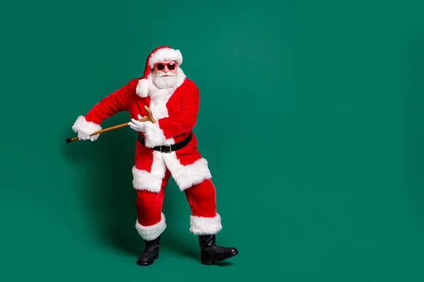 Uzun boylu, yakışıklı, güzel, neşeli Noel Baba 'nın elinde bastonla dans ederken eğlendiğini yeşil arka planda izole edilmiş bir bayram kutlamasını kutluyor. — Stok fotoğraf
