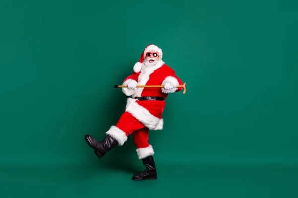 Uzun boylu, güzel, neşeli, neşeli, sakallı, neşeli, Noel Baba 'nın tahta sopayla dans etmesi, yeşil arka planda izole edilmiş keyifli bir ruh hali. — Stok fotoğraf
