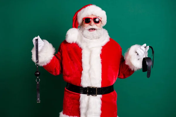 Portret jego atrakcyjny wesoły zabawny tłuszcz otyłość Santa nosić kostium gospodarstwa w ręce bicz narzędzia gry erotyka motyw strony świąteczne izolowane na zielonym tle kolor — Zdjęcie stockowe