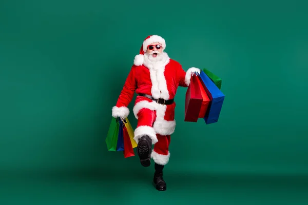 자신감 있는 산타 아버지가 가방을 운반하는 모습을 몸길이 전체로 본 산타 할아버지는 놀랍게도 12 월에 밝은 색상 배경에서 고립되었다. — 스톡 사진