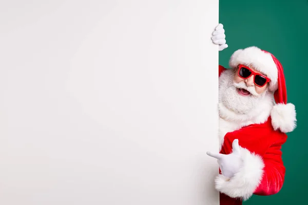 Foto de abuelo retirado elegante pelo gris barba directa dedo blanco tablero vacío promoción venta desgaste rojo traje de santa x-mas guantes abrigo sombrero de cristal aislado color verde fondo — Foto de Stock