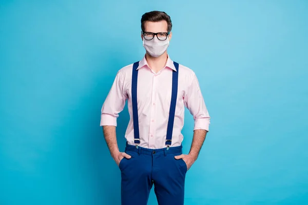 写真ハンサムなマッチョビジネス男性トレンド服男視力仕様手でポケットに滞在安全コロナウイルス発生着用医療用マスクピンクシャツサスペンダー隔離された青の色の背景 — ストック写真