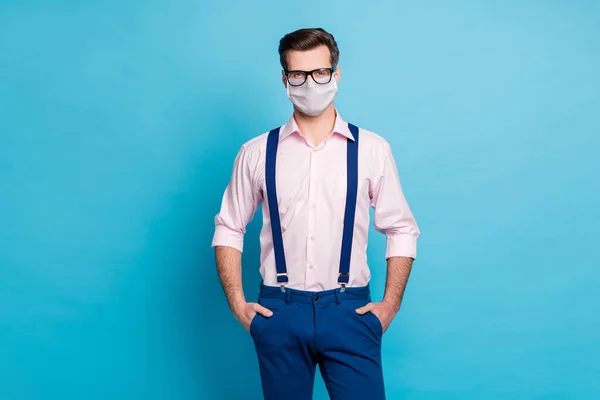 Foto knappe macho zakenman cool trend kleding man gezichtsvermogen zorg specs blijven veilig corona virus uitbraak dragen roze shirt bretels broek medisch masker geïsoleerde blauwe kleur achtergrond — Stockfoto