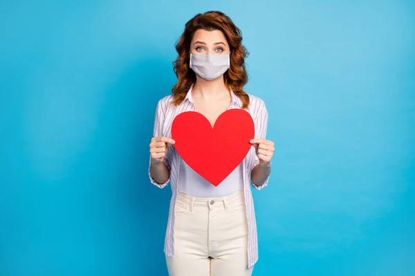 Portret van haar ze mooi golvend-harig meisje houden in handen groot papier hart dragen wit medisch masker zorg over stop covid infectie verspreid geïsoleerd op glanzende blauwe kleur achtergrond — Stockfoto