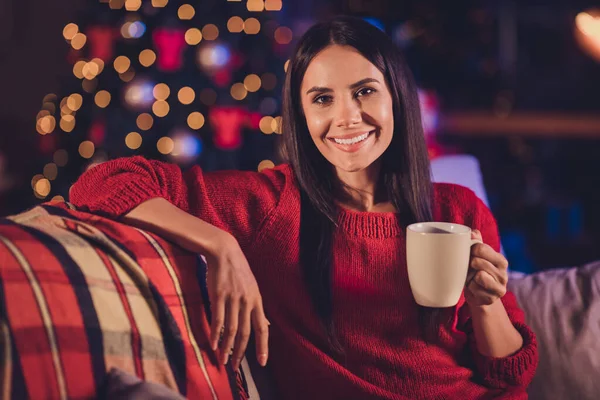 Portrait photo d'une femme détendue tenant une tasse dans une main assise sur un canapé à la maison avec des décorations de Noël — Photo