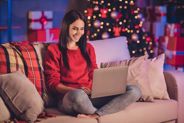 Fotoporträt einer Frau auf Sofa in Lotus-Pose mit Laptop mit Weihnachtsdekoration im Inneren — Stockfoto