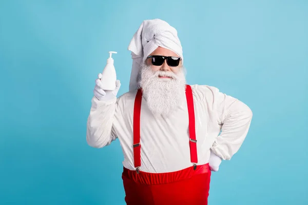 Fotografie důchodce starý tlustý muž šedé vousy držet mýdlo antiseptické láhev připravit umýt ruce kontakt lidé nosí Santa x-mas kostým ručník turban suspender sluneční sklo izolované modré barvy pozadí — Stock fotografie