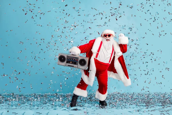 Pełna długość zdjęcie emeryta dziadek niedbały taniec podnieść pięść confetti trzymać retro radio nosić czerwony Santa X-mas kostium szelki okulary czapka buty spodnie odizolowany niebieski kolor tło — Zdjęcie stockowe