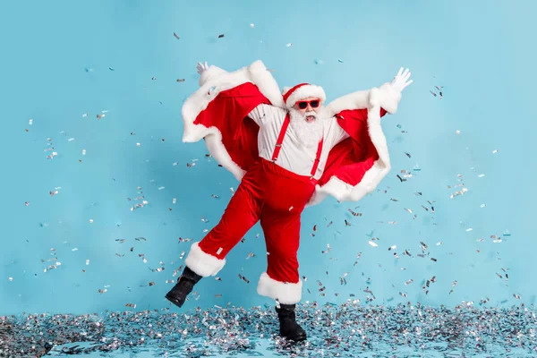 Lunghezza completa foto di pensionato vecchio uomo grigio barba pazzo club danza alzare le mani coriandoli usura Santa x-mas costume bretella stivali occhiali da sole cappello stivali pantaloni isolato colore blu sfondo — Foto Stock