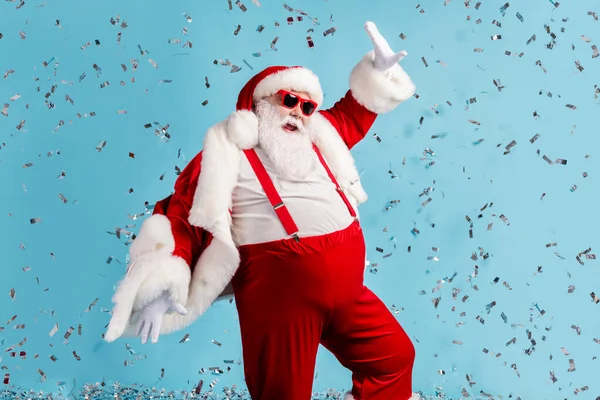 Zdjęcie emeryta starzec szary broda niedbały biegun północny zamknięty party dance zabawy kolorowe konfetti nosić Santa X-mas kostium szelki czapka sunglass odizolowany niebieski kolor tło — Zdjęcie stockowe