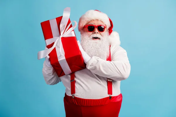 Portret van hem hij mooie aantrekkelijke vrolijke vrolijke wit-harige Santa vader houden in handen feestelijke rode geschenkdoos december traditie geïsoleerde heldere levendige glans levendige blauwe kleur achtergrond — Stockfoto