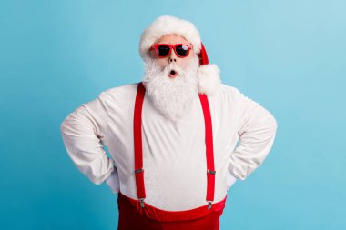 Photo of pensioner old man grey beard hands hips self-assured shock late wake up present delivery wear santa costume red suspenders spectacles white headwear isolated blue color background clipart