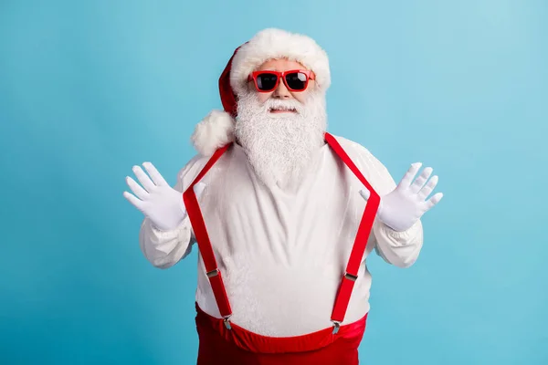 Portrait of his he nice attractive cheerful cheery funky comic white-haired Santa pulling suspenders having fun fooling good mood isolated over bright vivid shine vibrant blue color background