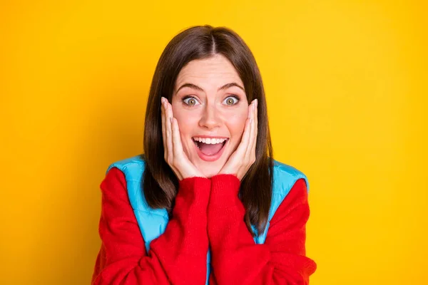 Foto de surpreendido menina hipster toque mãos rosto impressionado maravilhoso temporada pechincha desgaste vermelho suéter isolado sobre brilhante brilho cor fundo — Fotografia de Stock