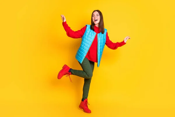 Pleine taille photo du corps de mignonne belle jeune dame rayonnant sourire regarder espace vide danse club partie porter pantalon vert gilet bleu rouge pull bottes isolé couleur jaune vif arrière-plan — Photo