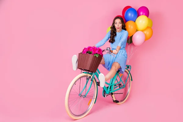 Volledige lichaamsomvang uitzicht van aantrekkelijke vrolijke golvende dame rijden fiets zonder benen leveren feestelijke feestelijke feestelijke decoratie hebben plezier grimacing geïsoleerde roze pastel kleur achtergrond — Stockfoto