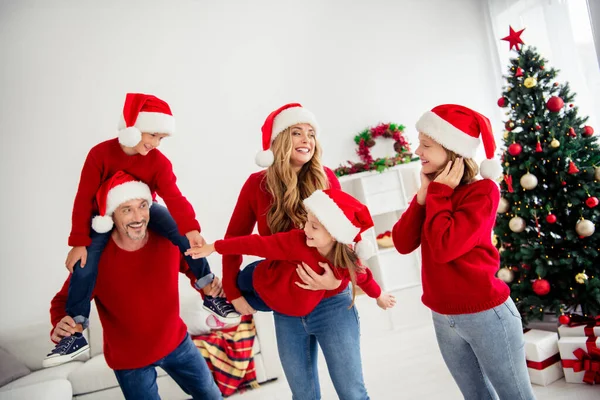Noel arifesinde Noel Baba 'nın küçük çocuklarla oynaması, el ele tutuşması, el ele tutuşması, Noel Baba şapkasını evin içinde geleneksel süslerle takması. — Stok fotoğraf