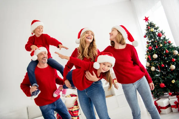 Glad familj gratulerar varandra på julafton nära dekorerad julgran närvarande lådor leka tillsammans på vintern. Mor håller dotter låtsas ett plan son sitter på fäder hals — Stockfoto