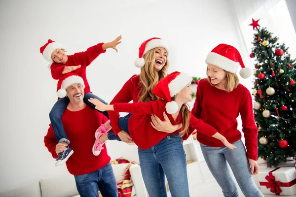 Friendly family greeting each other near decorated with baubles christmas tree playing together in winter. Mother holding daughter pretending a plane son sitting on fathers neck — Stock Photo, Image