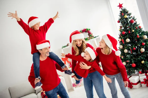 Mooie glimlachende familie die thuis speelt versierd met kerstballen kerstboom en groenblijvende krans die samen lachen. Moeder houden dochter doen alsof een vliegtuig zoon zit op vaders nek — Stockfoto