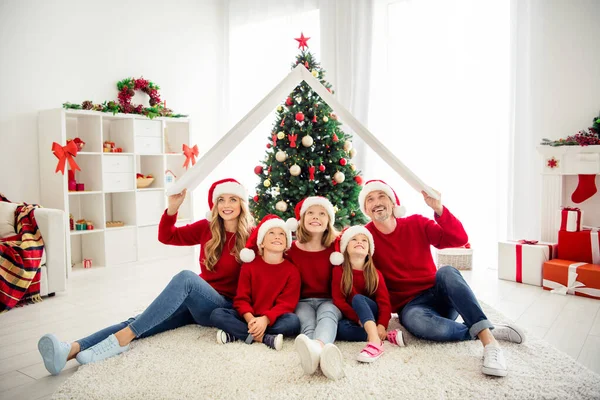 Erkek ve kız kardeşlerin kış zamanlarını aileleriyle geçirdikleri portre fotoğrafı. İki kız ve oğul gülümsüyor. Süslü Noel ağacının yanında oturuyorlar. Evde hediye kutuları var. — Stok fotoğraf