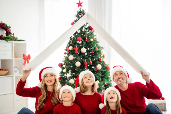 Portret foto van mooie ouders broer zussen besteden tijd vieren wintervakantie dragen rode hoofddeksels en warme truien zitten op kerstboom achtergrond — Stockfoto