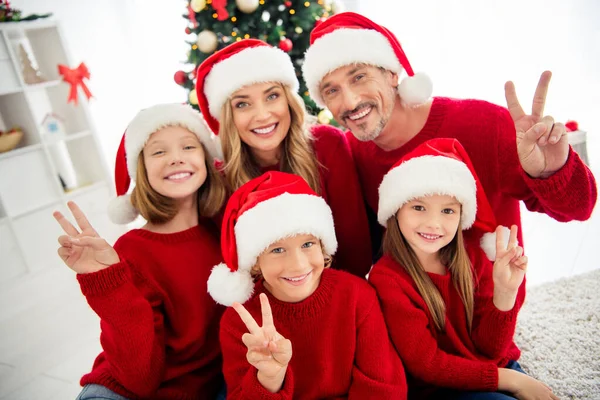 Foto van een grote gelukkige familie vijf mensen verzamelen van drie kleine kinderen show v-teken glimlach dragen x-mas hoofddeksel rode trui in huis woonkamer boom slinger vele aanwezig dozen binnen — Stockfoto