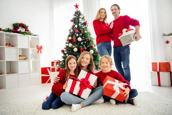 Fotografie plné velké rodiny pět lidí sbírat tři malé děti držet dárky mazlit rodiče táta držet tašku hračky nosit červené džíny doma obývací pokoj mnoho dárkových krabic uvnitř — Stock fotografie