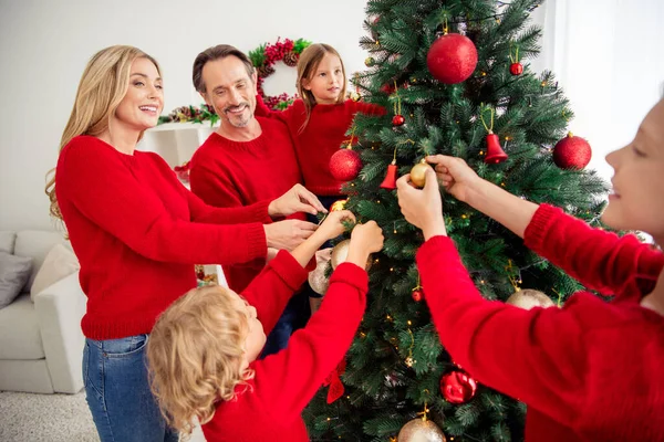 Foto van een grote familie vijf mensen ontmoeten drie kleine kinderen glimlachen versieren x-mas boom hold hangen speelgoed klokken sfeer slinger dragen rode trui jeans in huis woonkamer binnen — Stockfoto