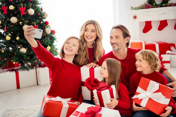 Fotografie plné velké rodiny pět lidí shromáždění tři malé děti držet krabice luk stuha dcera střílet selfie nosit červený jumper v zdobené domácí obývací pokoj x-mas strom uvnitř — Stock fotografie