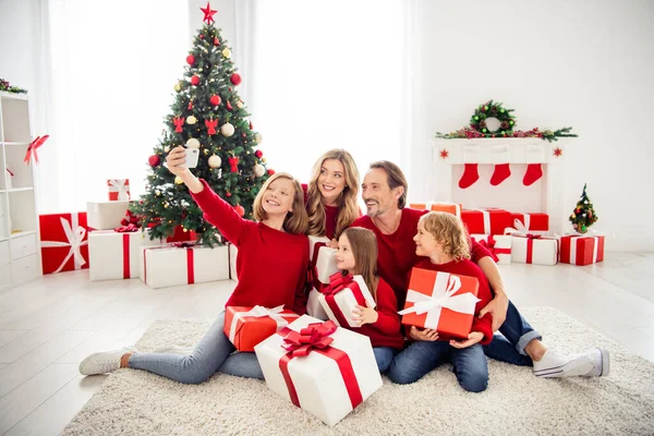 Foto av hela stora familjen fem personer möte älskare tre små barn hålla gåvor dekorerade pilbåge band dotter ta skjuta selfie bära röda jumper jeans i hemmet vardagsrum x-mas träd inomhus — Stockfoto