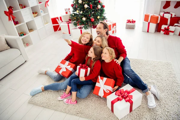 Foto van volledige grote familie vijf mensen verzamelen van drie kleine kinderen houden geschenken strik lint mam maken shoot selfie dragen rode trui jeans in ingerichte woonkamer x-mas boom lichten binnen — Stockfoto