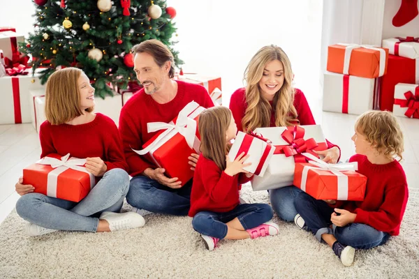 Foto van het hele gezin vijf mensen verzamelen drie kleine kinderen zitten tapijt wisselen grote dozen aanwezig dragen rode trui jeans in woonkamer x-mas boom slinger vele geschenken binnen — Stockfoto