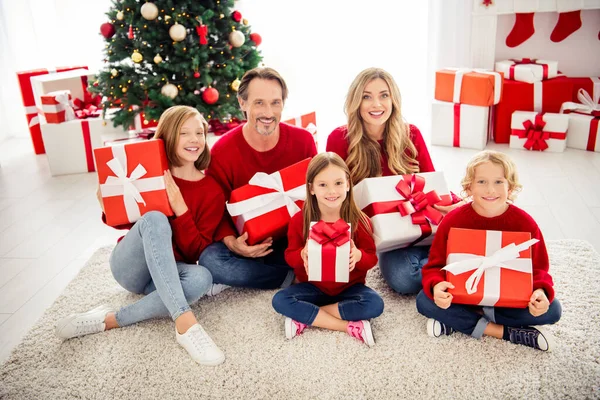 Foto de familia grande completa cinco personas que reúnen a tres niños pequeños se sientan piso sostienen regalos coloridos sonríen usan pantalones vaqueros jersey rojo en la sala de estar guirnalda de árbol de x-mas muchos regalos en el interior — Foto de Stock