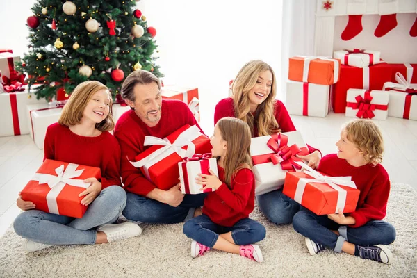 Foto van hele grote familie vijf mensen ontmoeten drie kleine kinderen zitten tapijt hold uitwisseling cadeautjes meisje dragen rode trui jeans in woonkamer x-mas boom slinger vele cadeautjes binnen — Stockfoto