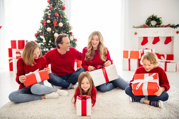 Foto van volle grote familie vijf mensen verzamelen drie kleine kinderen zitten vloer wit tapijt ontvangen cadeautjes dragen rode trui jeans in ingerichte woonkamer x-mas boom veel dozen lichten binnen — Stockfoto