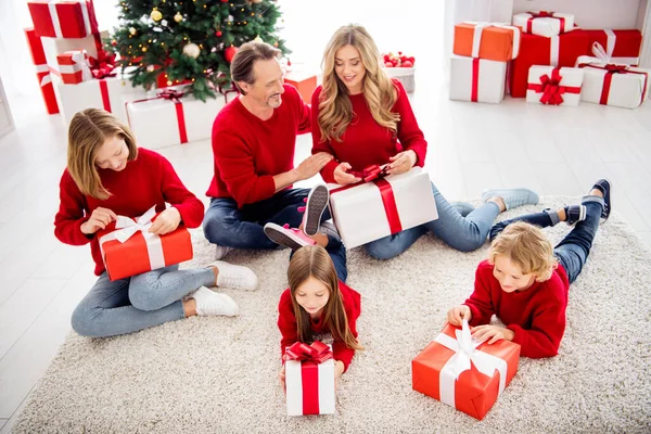 Foto van een hele grote familie vijf mensen ontmoeten drie kleine kinderen liggen vloerkleed unboxing cadeautjes dragen rode trui jeans in ingerichte woonkamer x-mas boom veel dozen lichten binnen — Stockfoto