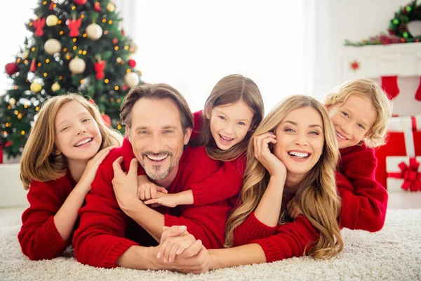 Foto van een grote familie vijf mensen verzamelen van drie kleine kinderen hand in hand liggen vloerkleed tandenglimlach omarmen dragen rode trui in de ingerichte woonkamer x-mas boom lichten giftboxen binnen — Stockfoto