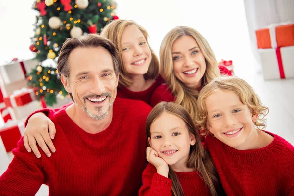 Büyük aile fotoğrafı. Beş kişi bir araya geliyor. Üç küçük çocuk. Parlak dişli kız el yanağı, oturma odasında kırmızı kazak giyiyor. — Stok fotoğraf