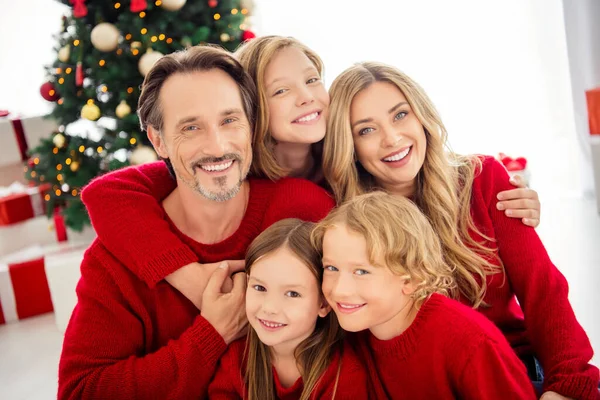 Foto van een grote familie vijf mensen verzamelen van drie kleine kinderen omhelzen knuffel zit vloer glanzend glimlachen dragen rode trui in versierde woonkamer x-mas boom slinger gift dozen binnen — Stockfoto