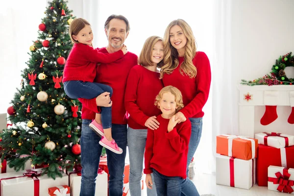 Foto van het hele gezin vijf mensen ontmoeten drie kleine kinderen vader knuffelen dochter jongen hand in hand moeder dragen rode trui jeans in woonkamer x-mas boom lichten gift dozen binnen — Stockfoto