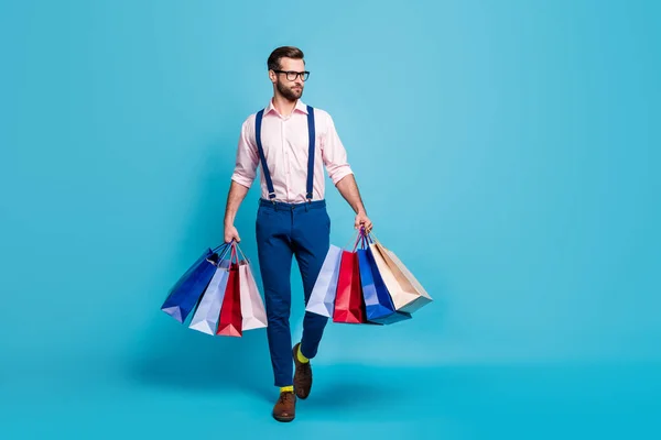 Foto de cuerpo completo de hombre de negocios guapo trabajador llevar muchas bolsas comprar ropa vacaciones centro comercial usar especificaciones camisa tirantes pantalones botas calcetines aislados pastel azul color fondo — Foto de Stock