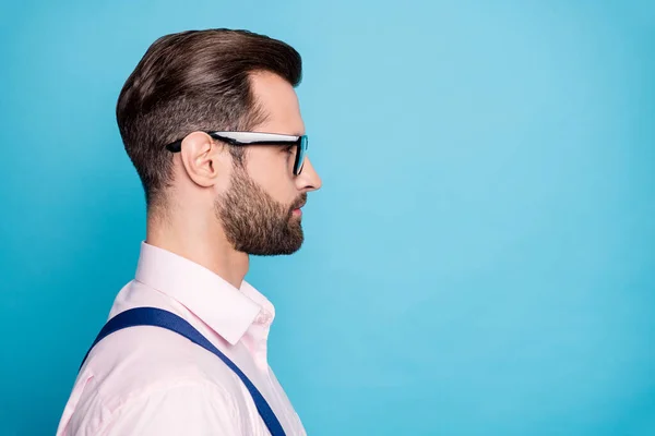 Primer plano foto de perfil del hombre de negocios guapo exitoso jefe joven jefe trabajador mirada espacio vacío seria expresión facial desgaste especificaciones camisa rosa tirantes aislado fondo de color azul — Foto de Stock