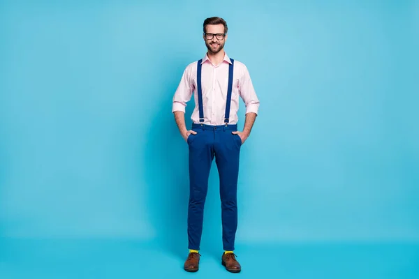 Full length photo of handsome business man trend clothes beaming smile eyesight specs hands pockets wear pink shirt suspenders pants footwear yellow socks isolated blue color background — Stock Photo, Image