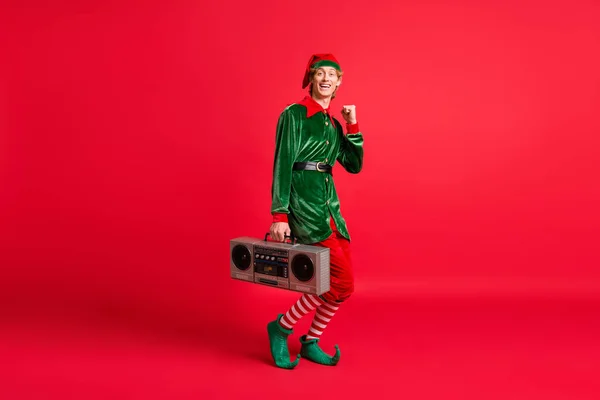 Full längd foto av galna nisse hålla bom box höja nävar jul jul händelse koncept isolerad på röd färg bakgrund — Stockfoto