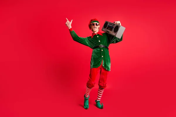 Çılgın elf 'in tam boy fotoğrafı. Kaset çalar. Parlak kırmızı arkaplanda izole edilmiş x-mas şarkılarını dinle. — Stok fotoğraf