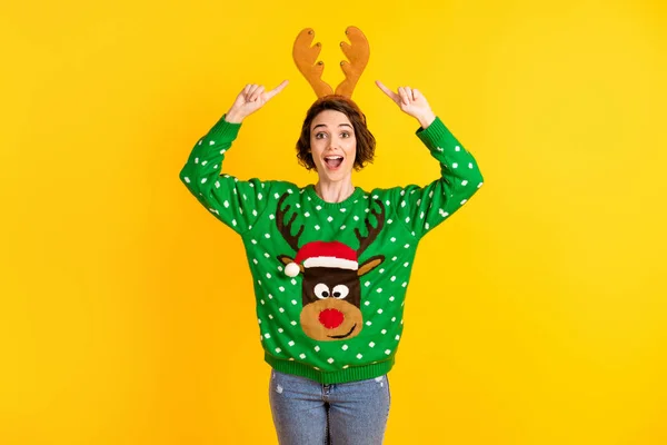 Astonished crazy girl deer green x-mas sweater point finger reindeer headband receive gift present theme costume party wear denim jeans isolated bright shine color background — Stock Photo, Image