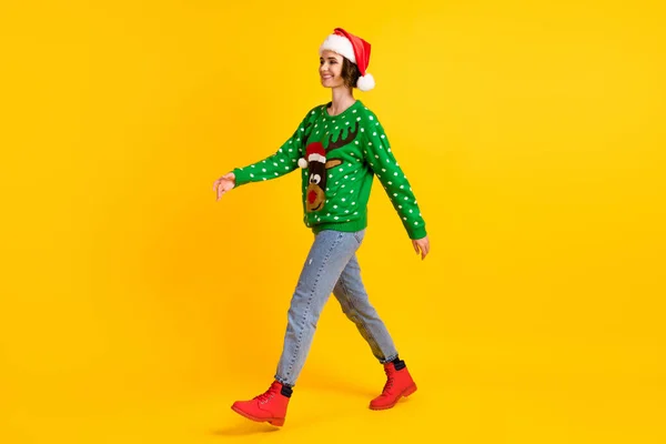 Повна довжина профілю сторона фото позитивної дівчини в головній убірці Санта-Клауса йдуть пішки копіспазмом Різдвяна тема вечірки носіння оленів светр джинси чоботи ізольовані яскравий блискучий колір фону — стокове фото