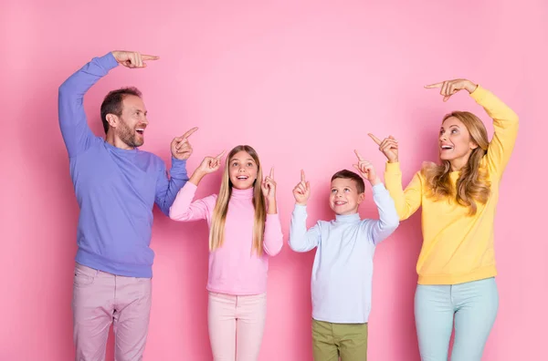 Foto von überrascht Mama Papa kleine Kinder zeigen Zeigefinger nach oben leeren Raum isoliert über pastellrosa Farbe Hintergrund — Stockfoto