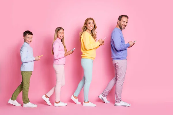 Full body profile side photo of dad mom small kids go with cell phone isolated over pink pastel color background